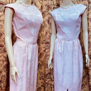 May include: A pink sleeveless dress with a floral pattern. The dress has a fitted bodice and a full skirt. The dress is made of a silky fabric.