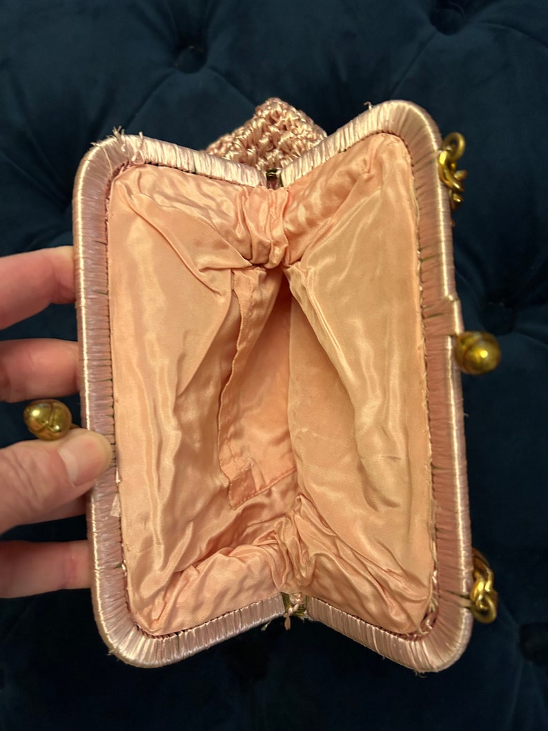 May include: A pink crocheted evening bag with a satin lining and a gold clasp.