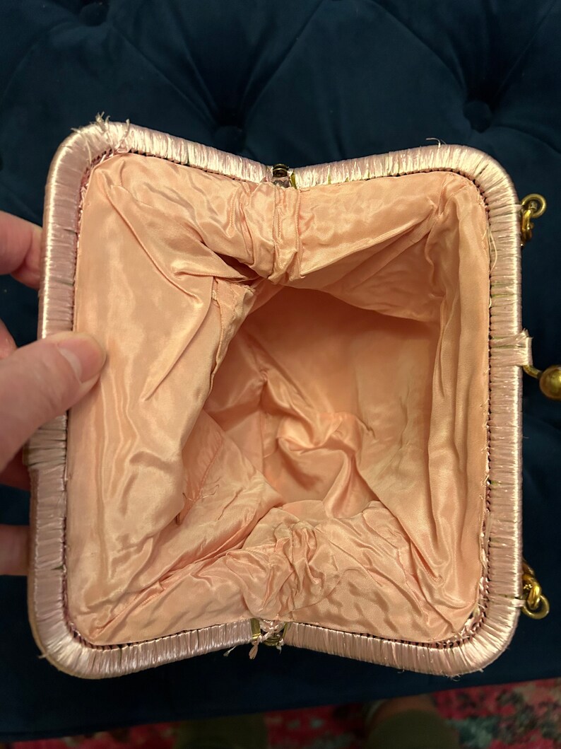 May include: A pink satin evening bag with a gold clasp and chain. The bag is open and the inside is lined with a pale pink fabric.