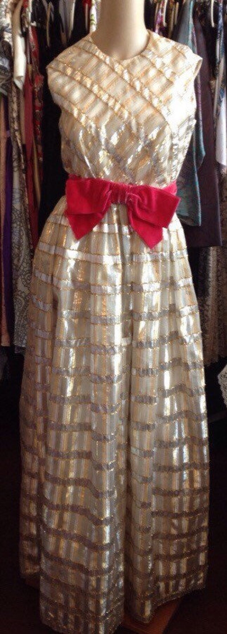 K&ouml;nnte beinhalten: Ein gold-wei&szlig;es Paillettenkleid mit einer roten Samtschleife an der Taille.