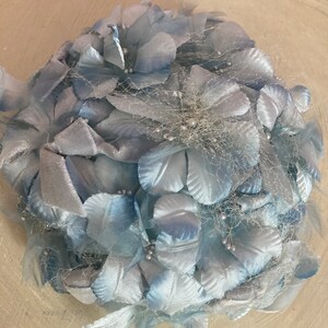 May include: A light blue vintage hat made of fabric flowers and netting. The hat is decorated with small silver beads.