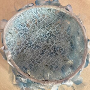 May include: A light blue hat with a lace crown and a trim of blue feathers.