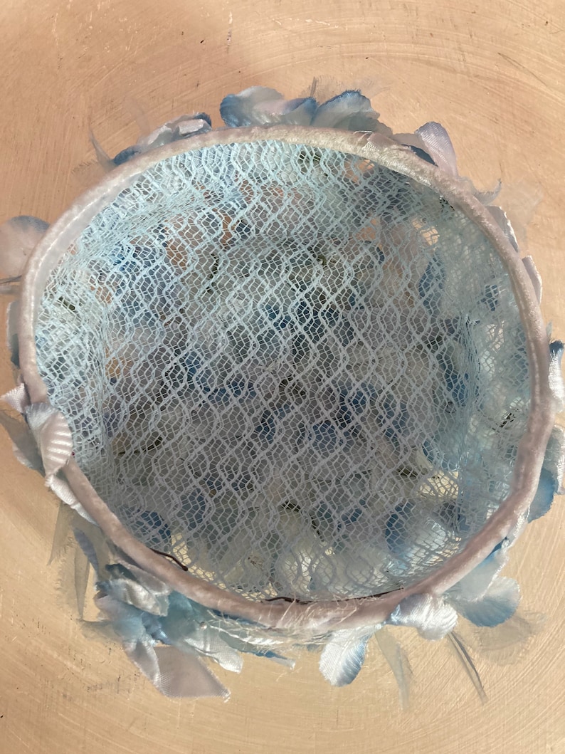 May include: A light blue hat with a lace crown and a trim of blue feathers.