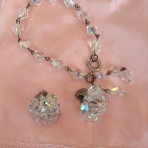 May include: A set of vintage crystal jewelry featuring a bracelet and a pair of earrings. The bracelet is made of clear crystal beads strung on a silver chain. The earrings are also made of clear crystal beads and have a silver clasp.