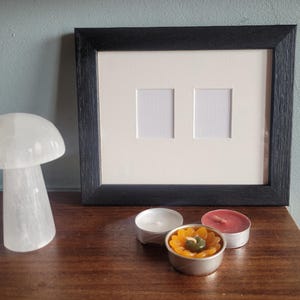 Moderne zwarte lijst voor 2 pasfoto's. Kusthout met een open nerfafwerking. Houtgebeitst, niet in plastic verpakt. Perfecte cadeaus voor koppels.