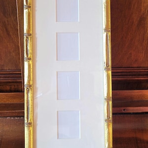 May include: A gold picture frame with a raised bamboo design. The frame has four rectangular openings for photos.