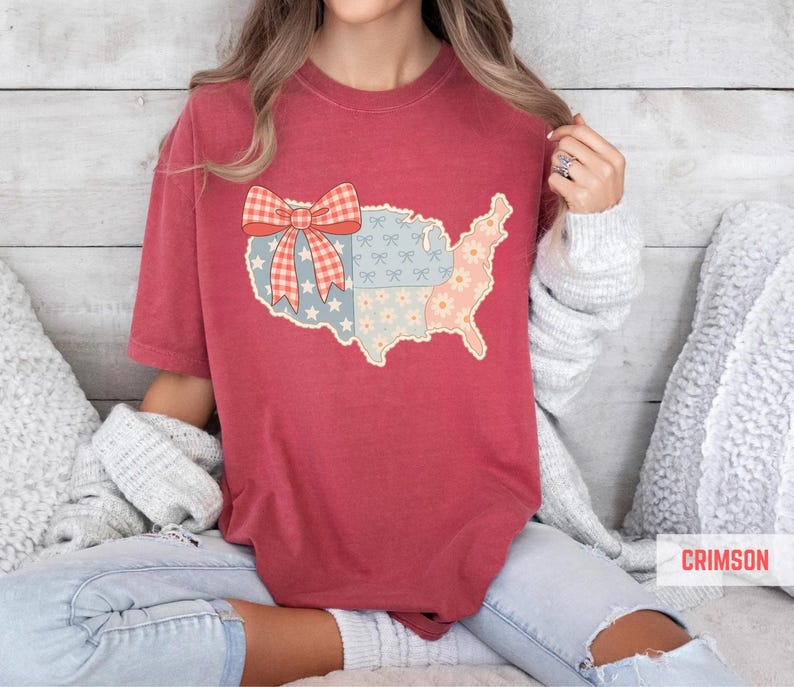 a woman sitting on a bed wearing a red shirt with a map of the united