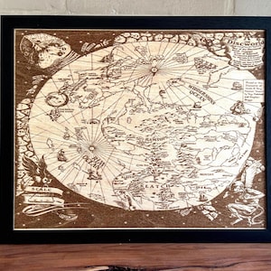 May include: A square framed wall art piece featuring a laser-engraved wooden map of the Discworld. The map displays intricate geographical details, including the Widdershins Ocean, Rim Ocean, and various continents, with text labels and decorative illustrations.