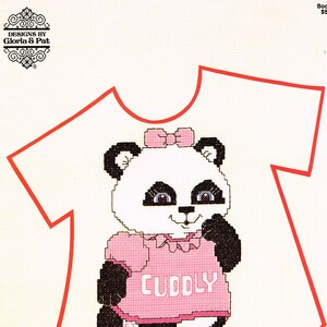 May include: A cross-stitch pattern for a t-shirt featuring a cute panda bear wearing a pink shirt with the word "CUDDLY" on it. The pattern is from the "Shirt Tales" collection.