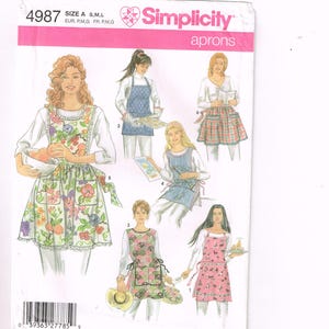 May include: Simplicity apron sewing pattern, size A, S, M, L. The pattern features illustrations of aprons in various styles, including floral, plaid, and solid designs. The aprons are shown with different pocket and trim details.