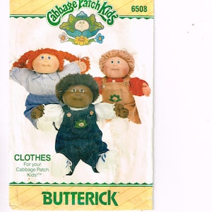 May include: Vintage Butterick pattern for Cabbage Patch Kids clothes. The pattern features three Cabbage Patch Kids dolls wearing different outfits. The packaging has the Cabbage Patch Kids logo and the word "CLOTHES" and "BUTTERICK".