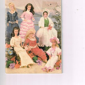 May include: A vintage book cover featuring six fashion dolls in crocheted outfits. The cover has the title "YESTER-Y-E-A-R" in pink letters. The dolls are dressed in various colors, including blue, pink, white, and red.