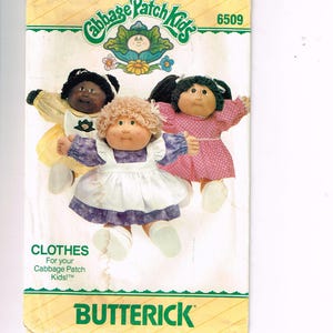 May include: A vintage Butterick pattern for Cabbage Patch Kids clothes. The cover shows three dolls in various outfits. The Cabbage Patch Kids logo is at the top, with the word "CLOTHES" and the Butterick logo at the bottom.