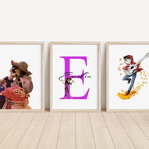 Peut inclure: Trois impressions encadrées représentant des personnages du film d'animation Coco. La première impression montre un couple de squelettes qui s'embrasse. La deuxième impression présente une grande lettre E violette avec le nom "Emilia" écrit en noir. La troisième impression montre un personnage de dessin animé jouant de la guitare avec des feuilles qui tombent.