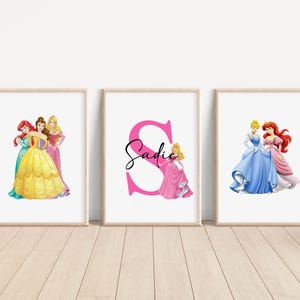 May include: Three printable wall art prints featuring Disney princesses. The first print shows Ariel, Belle, and Aurora. The second print features a pink letter S with the name Sadie. The third print shows Cinderella and Ariel.