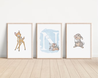 Puede incluir: Tres impresiones enmarcadas con un fondo de acuarela azul. La impresión de la izquierda presenta a Bambi, la impresión del medio presenta la letra N con Thumper y una flor, y la impresión de la derecha presenta un conejo.