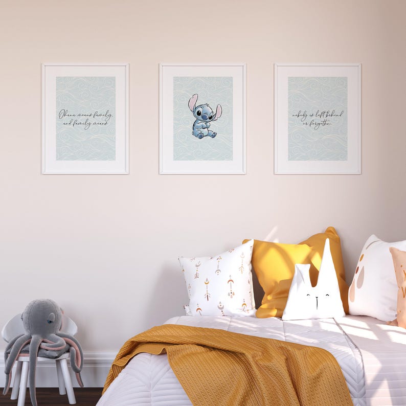 May include: Three framed prints with a blue and white cartoon character and two inspirational quotes. The quotes are "Ohana means family and family means nobody gets left behind or forgotten." The prints are hanging on a white wall above a bed with yellow and white pillows.