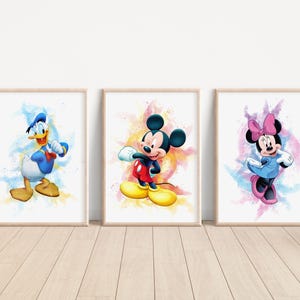 Op de afbeelding: Drie aquarelprints met Mickey Mouse, Minnie Mouse en Donald Duck. Elke print heeft een kleurrijke achtergrond met een witte rand.