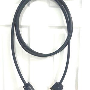 May include: A black electrical extension cord with a three-prong plug on one end and a three-prong outlet on the other end.