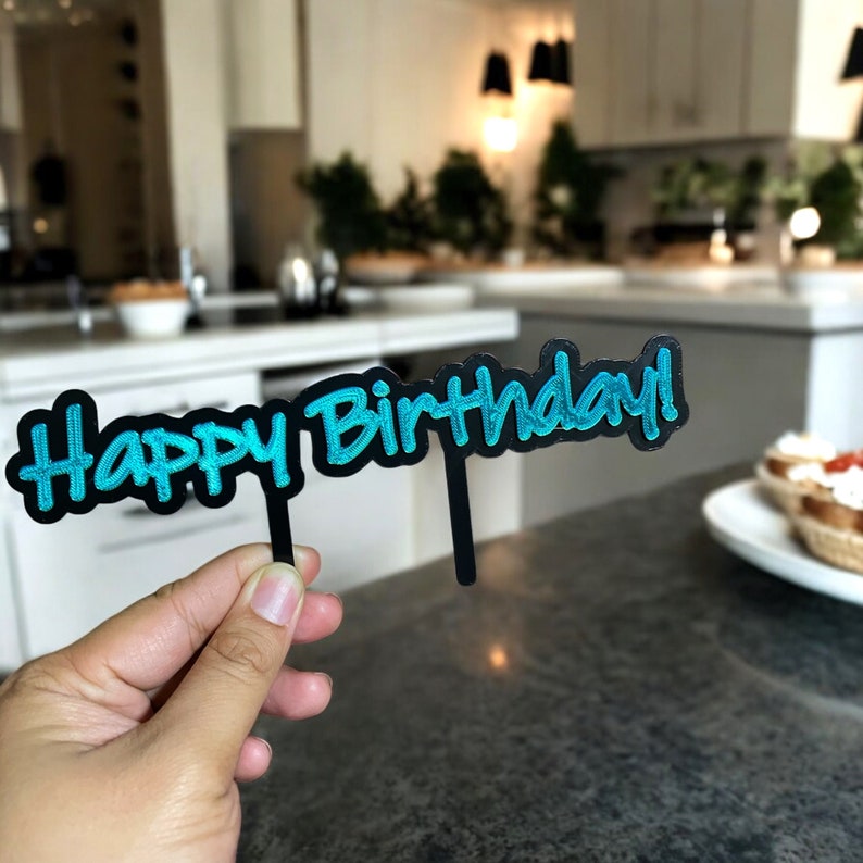 Peut inclure: Un topper de g&acirc;teau noir avec les mots "Happy Birthday!" &eacute;crits en lettres turquoise.