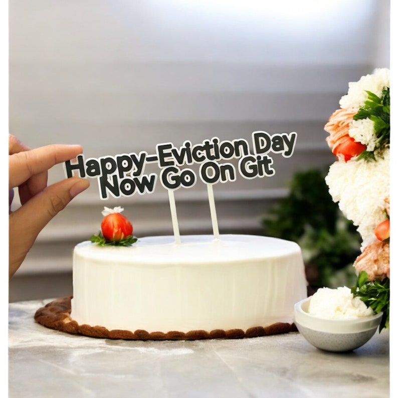 Peut inclure: Un g&acirc;teau blanc avec une fraise sur le dessus et des d&eacute;corations de g&acirc;teau noires qui disent "Happy-Eviction Day Now Go On Git"