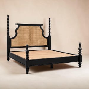 May include: A black bed frame featuring a tall headboard with a natural light brown woven cane panel. The frame includes four tall, turned posts with decorative finials at the top and a flat, light-colored wooden platform base for a mattress.