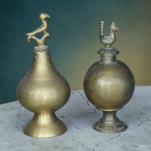 May include: A white ceramic mug with a black handle and the text "But First, Coffee" in a bold, black font. The mug is set against a blurred background, suggesting a cozy setting.