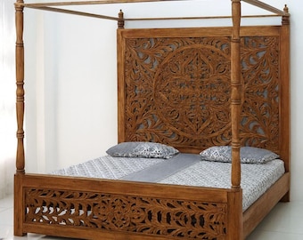 Pode incluir: Uma cama de dossel de madeira com intrincados desenhos florais esculpidos na cabeceira e na peseira. A estrutura da cama é de cor castanha quente, e a cama é feita com um edredão estampado e duas almofadas.