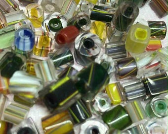 May include: A collection of colorful glass beads in various shapes and sizes. The beads feature stripes of yellow, green, white, and red. Some beads are clear, while others are opaque. Ideal for jewelry making or craft projects.