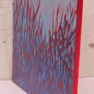 K&ouml;nnte beinhalten: Ein rechteckiges Gem&auml;lde auf einer Holzplatte mit rot bemalter Kante. Das Kunstwerk zeigt ein dichtes Muster aus dunkelblauen vertikalen Linien, die &uuml;ber einen hellblauen Hintergrund gelegt sind, mit kleinen orangefarbenen Formen.