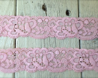 May include: Pink lace trim with a delicate floral pattern. The lace is soft and has a slightly scalloped edge.