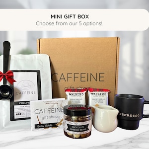 May include: A brown cardboard box with the text "CAFFEINE gift shop" on the front. The box contains a variety of coffee-related items, including coffee beans, coffee filters, and a coffee scoop. The box is a mini gift box and is available in five different options.