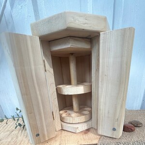 May include: A wooden cabinet with two doors that open to reveal a rotating shelf with six compartments on each level. The cabinet is made of natural wood and has a rustic look.