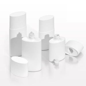 May include: A collection of white, oval-shaped eye drop bottles and caps. Some bottles have nozzles, while others are open. The caps are oval and angled. The bottles are arranged on a white surface.