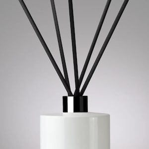 May include: White ceramic diffuser bottle with a black lid and black diffuser sticks.