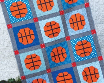 May include: A quilt pattern featuring a basketball design. The quilt is made up of squares with different patterns, including blue with white polka dots, gray with a white checkered pattern, and blue with a white geometric pattern. The basketballs are orange with black lines. The quilt is titled "Slam Dunk" and is numbered #176. The quilt pattern is from Cluck Cluck Sew.