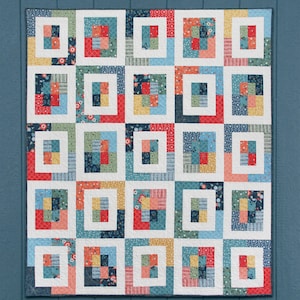 May include: A quilt pattern called "Windows" featuring a colorful patchwork design with a white background. The pattern is available in five sizes and can be made with a jelly roll, layer cake, or fat quarters.