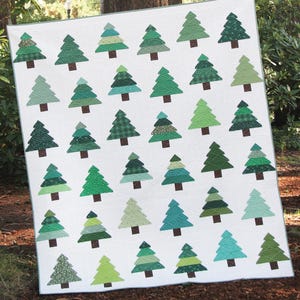 May include: A quilt pattern titled The Pines featuring a white background with rows of stylized evergreen trees in various shades of green. The trees have brown trunks and textured fabric patterns. The PDF document includes text and a red chicken logo.