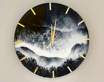 Peut inclure: Horloge en résine noire et blanche avec des accents dorés. Le cadran de l'horloge présente un design abstrait tourbillonnant ressemblant à des vagues.