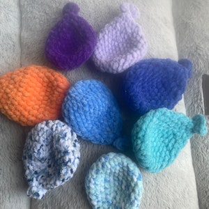May include: Eight crocheted balls in various colors, including purple, orange, blue, and light blue. The balls are made of soft yarn and have a textured surface.