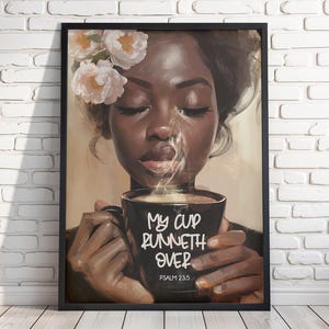May include: A framed art print depicts a woman with closed eyes, holding a black mug with steam rising. The mug reads "My Cup Runneth Over" and "Psalm 23:5". The woman has flowers in her hair.
