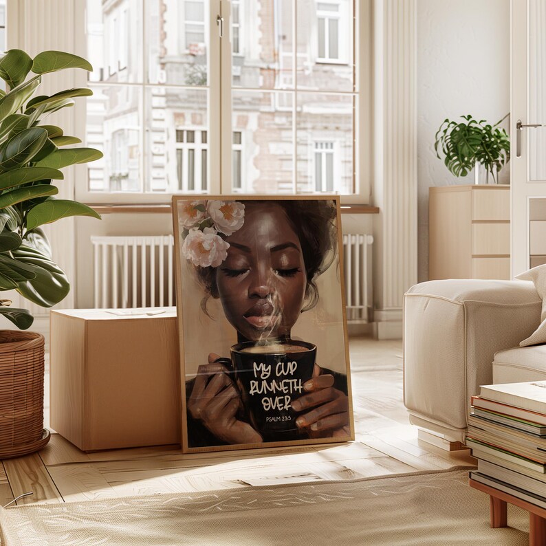 May include: A framed art print featuring a portrait of a person with flowers in their hair, holding a black mug with the text "My cup runneth over" and the Bible verse Psalm 23:5. The artwork has a warm color palette and is displayed in a well-lit room.