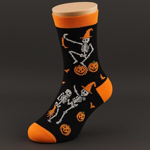 May include: Black Halloween socks with orange accents at the toe, heel, and cuff. The socks feature white skeleton graphics wearing orange witch hats, along with orange jack-o'-lanterns and bats.