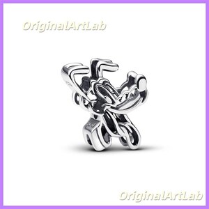 May include: A silver charm with a cartoon character design. The charm has a polished finish and detailed features, with a loop for attachment. The charm is likely made of sterling silver.