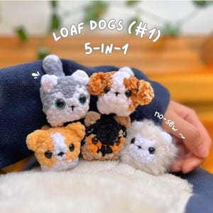 May include: Five small, handmade crochet dog toys in various colors, including white, gray, orange, and black. The toys are in the shape of dog faces. Text on the image reads "LOAF DOGS (#1) 5-IN-1 no-sew".