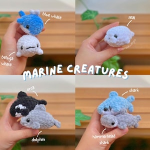 May include: A collection of small, plush, crocheted marine creatures including a blue whale, beluga whale, seal, orca, dolphin, shark, and hammerhead shark. The text "MARINE CREATURES" is displayed prominently, with labels identifying each animal.