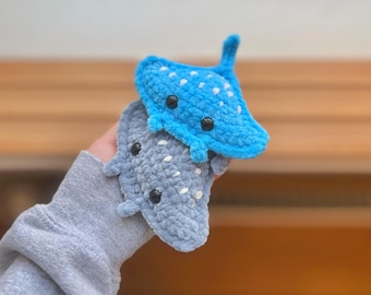 May include: Two crocheted stingray plushies. One is blue with white spots and the other is gray. Both have black eyes.