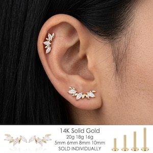 Peut inclure: Une boucle d'oreille grimpante en or avec une rangée incurvée de pierres claires taille marquise. Le texte 14K Solid Gold, 20g 18g 16g, 5mm 6mm 8mm 10mm, SOLD INDIVIDUALLY est visible, avec quatre tiges dorées à dos plat de longueurs variées.