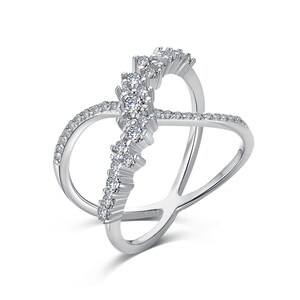 May include: A silver-colored ring with a unique crisscross design. The ring features a row of clear, sparkling stones set in a vertical line, with smaller stones outlining the curved bands. The ring is set against a white background.