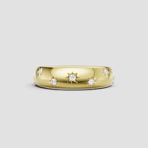 May include: A gold-colored ring with a domed shape. The ring is adorned with multiple star-shaped designs, each featuring a central, sparkling diamond. The ring's surface reflects light, highlighting its polished finish. A piece of jewelry.